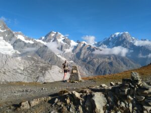 Person standing by stone pillar in front of mountains